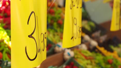 price tags at a market stall with blurred fresh produce in the background