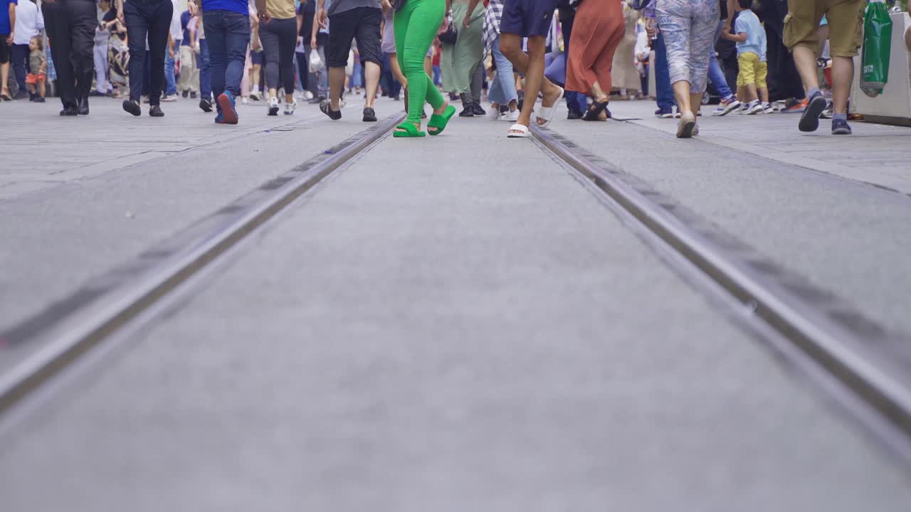 Human feet walking on crowded street.