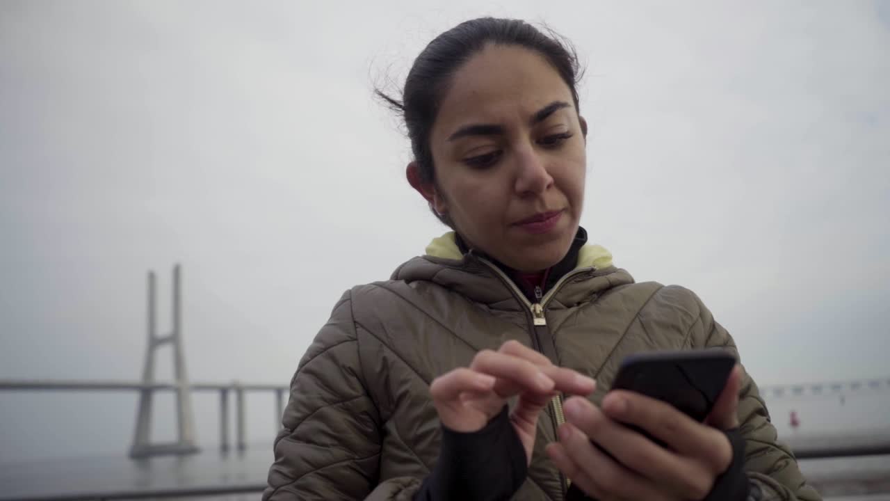 mujer hindú pensativa usando un teléfono inteligente al aire libre