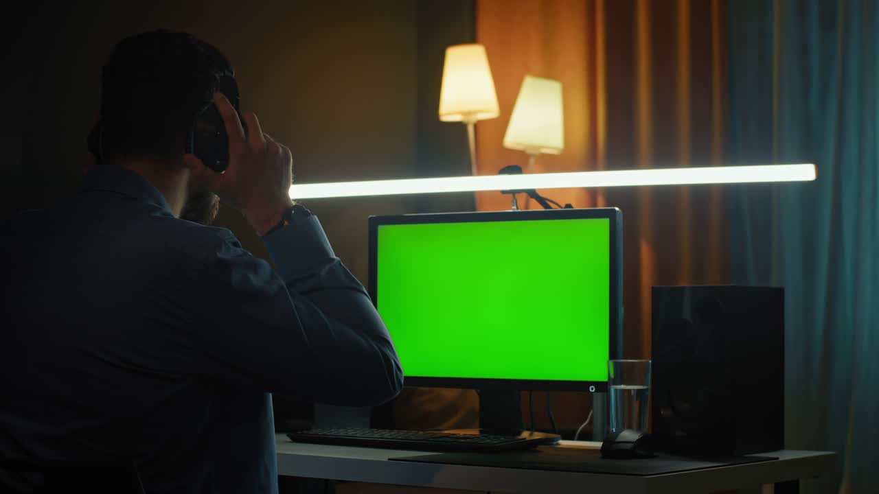 Concentrated young man in headphones with computer working at home office. Remote job, technology and people concept.