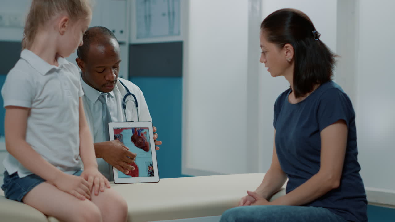Un dottore spiega l'anatomia del cuore a una paziente e a sua madre