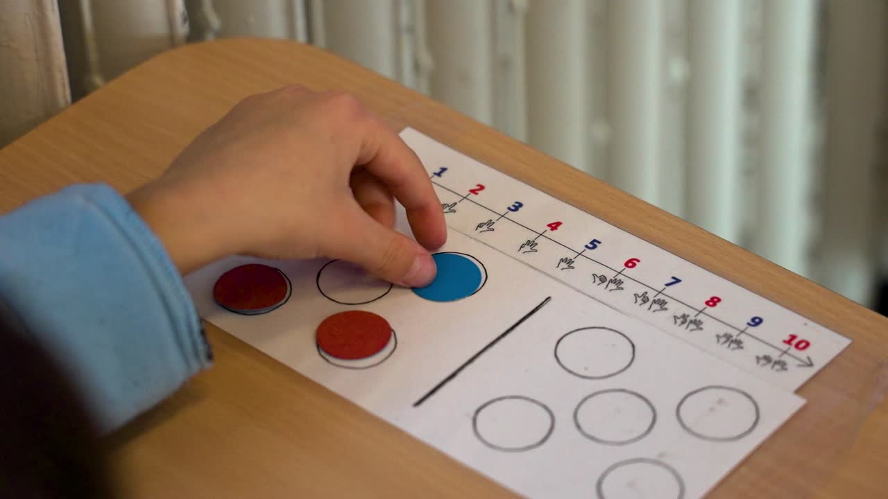 Child using math counting sheet with colorful counters