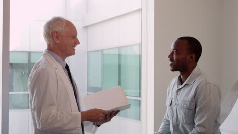 doctor meets with male patient in exam room shot on r3d