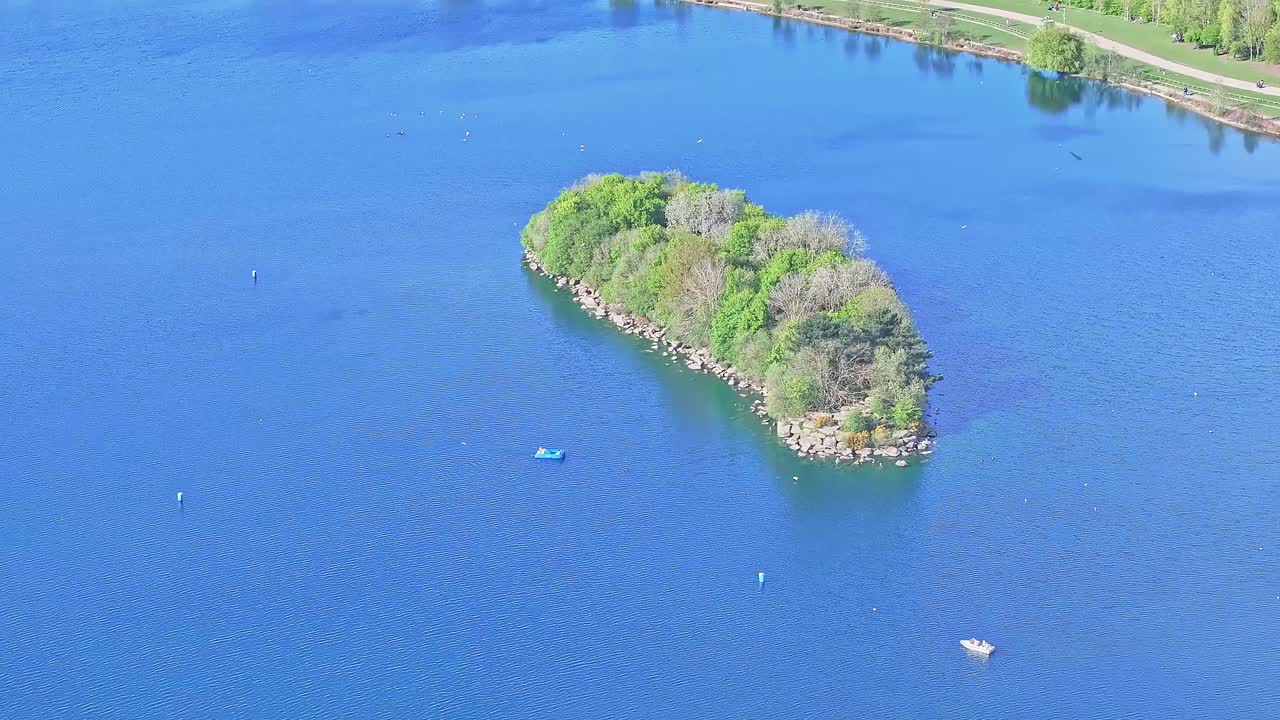 Aerial: small island on the lake during the day in Rother Valley Country Park in the Metropolitan Borough of Rotherham, South Yorkshire, England, crane down drone shot