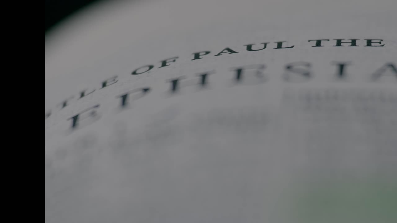 A shallow depth of field shot focusing on a specific verse in the Holy Bible. The clip evokes a sense of study, devotion, and finding meaning in the sacred text