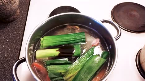 hand is adding stock to the soup and stirs the soup - cooking pork cabbage soup