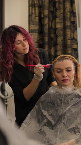 a hairstylist dyes a client's hair in a salon