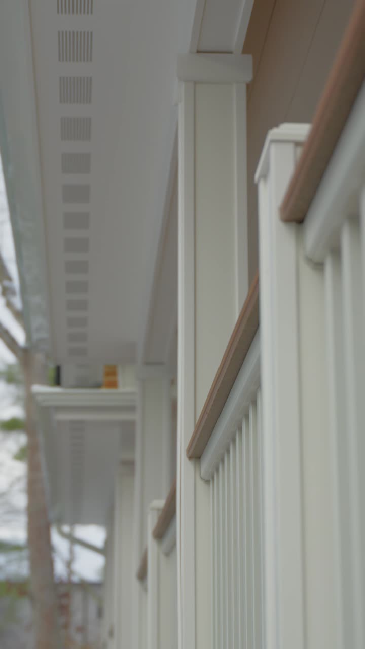 A smooth, cinematic vertical video captures a recently completed front porch on Long Island, New York, covered in fresh snow