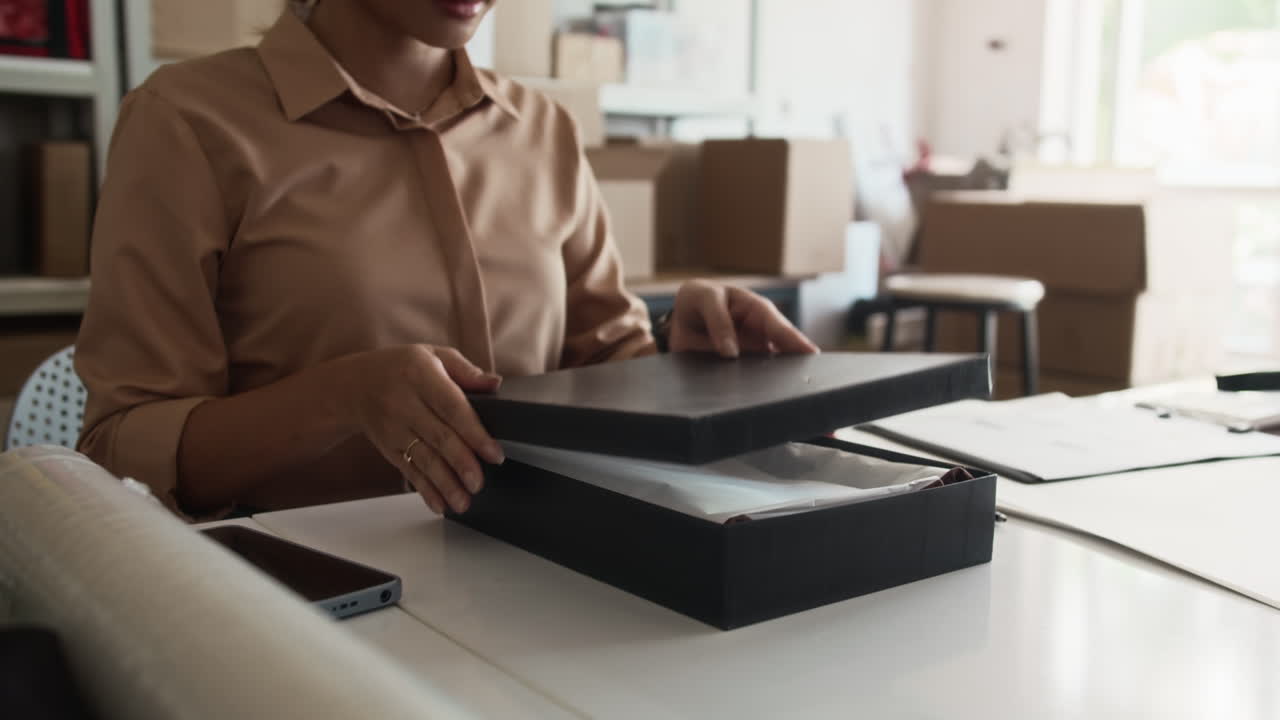 Delivery Worker Putting Clothes in Box for Shipping at Warehouse