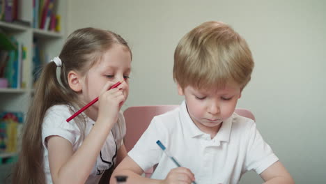 la hermana enseña al hermano pequeño a dibujar jugando a la escuela en casa