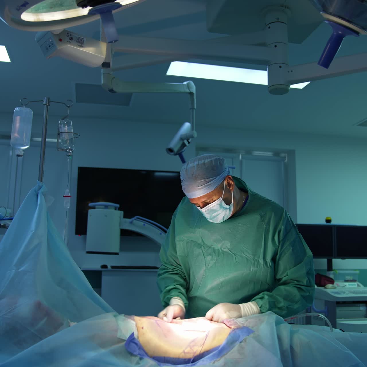 Liposuction procedure under surgical lamp. Professional doctor in medical uniform doing fat transfer operation. Surgery and resuscitation in hospital