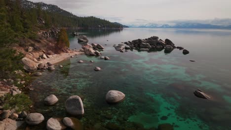 sunny winter day sand harbor south lake tahoe aerial drone california over large boulder rocks incline village crystal clear glassy turquoise water secret whale chimney kings beach static shot
