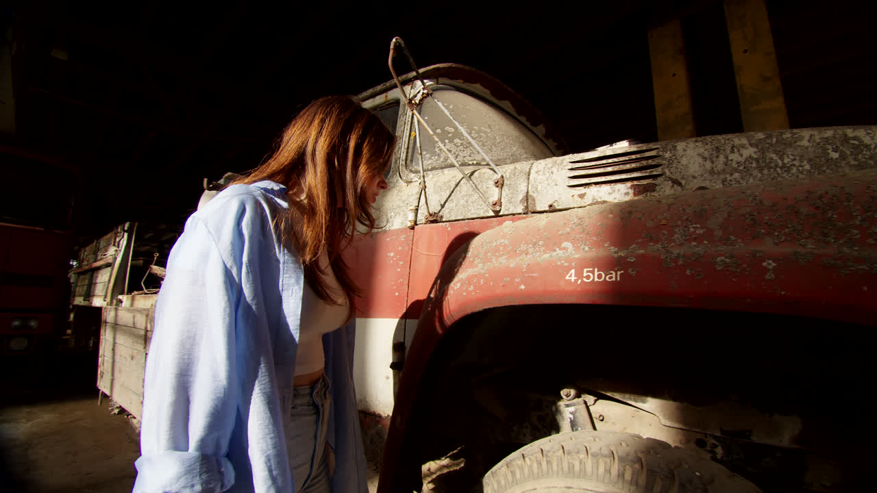 Woman Observing an Old Rusty Truck in an Abandoned Garage