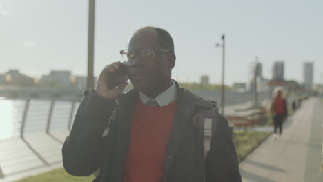 black businessman walking in city and talking on phone