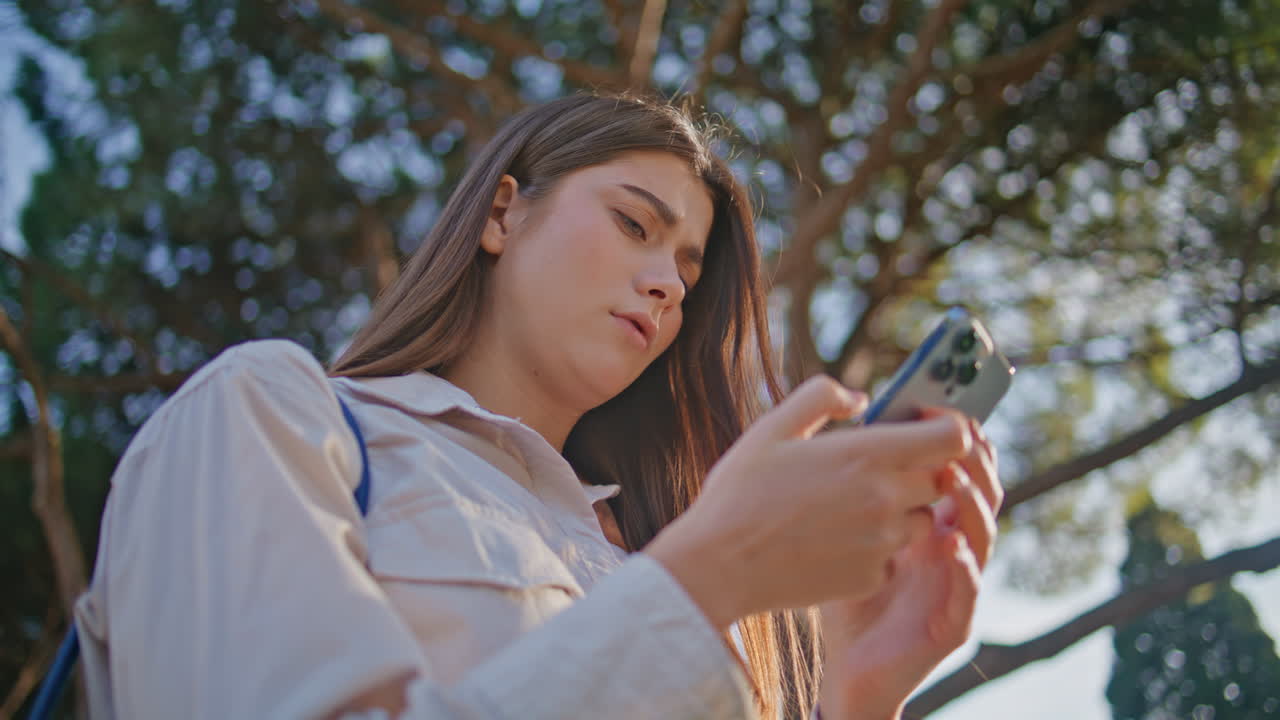 Frowning girl looking cellphone exploring park closeup. Woman reading smartphone
