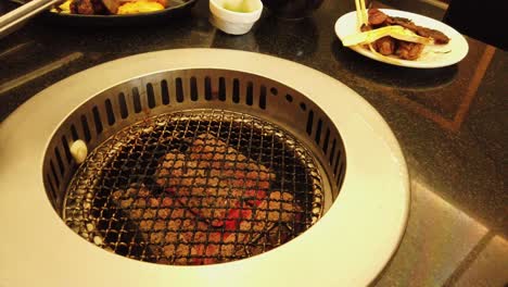 Primer-Plano-De-La-Cocina-Asiática-Barbacoa-De-Estilo-Japonés,-Con-Parrilla-De-Carbón-De-Autoservicio-Integrada-En-La-Mesa-Del-Cliente-En-Un-Restaurante