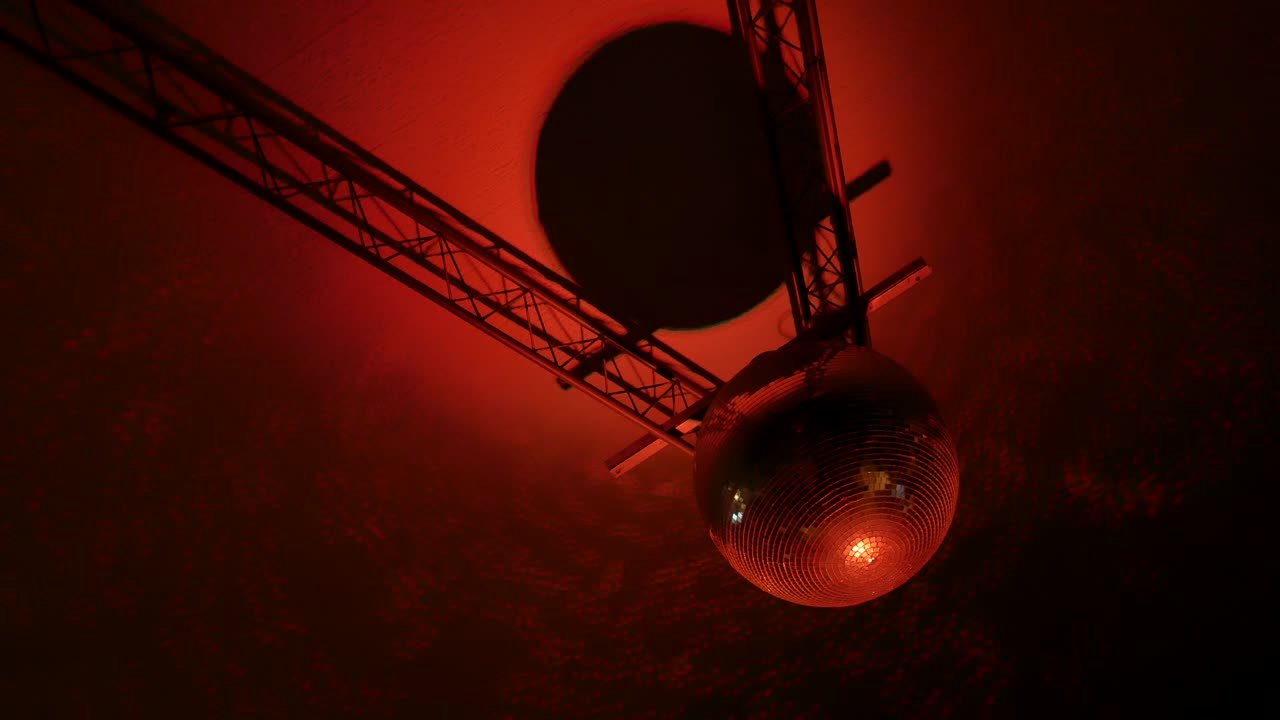 imágenes de una bola de discoteca de esfera de espejo giratoria con reflejos de luces de colores en el techo.