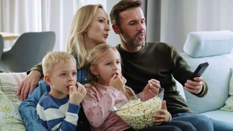 family with two children watching tv in living room