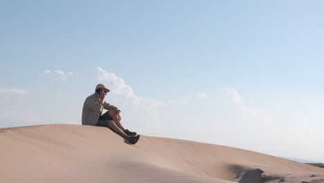man using smart phone with internet connection in the desert dunes alone