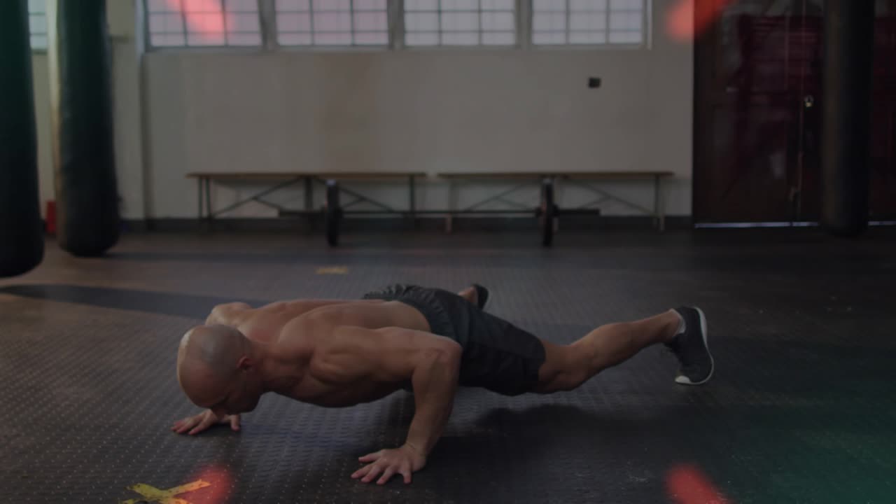 Uomo che inizia una posizione prona su un pavimento di gomma, facendo flessioni a ragno, mentre un HUD si concentra sul busto per il fitness