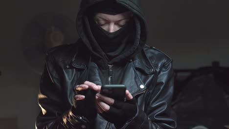 an angry person wearing a terrorist mask is using a phone