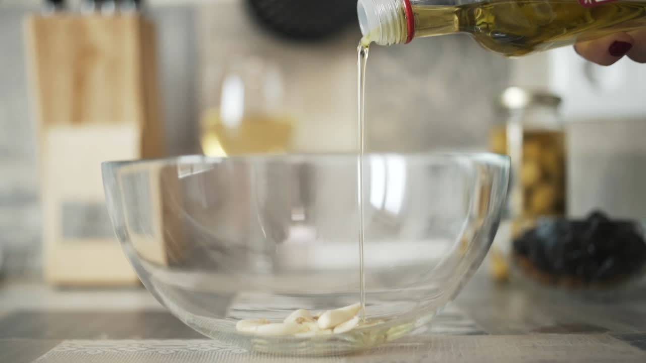 Pouring Olive Oil into Garlic in a Glass Bowl