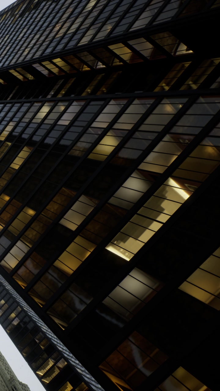 Modern office building with glass windows reflecting city lights at night