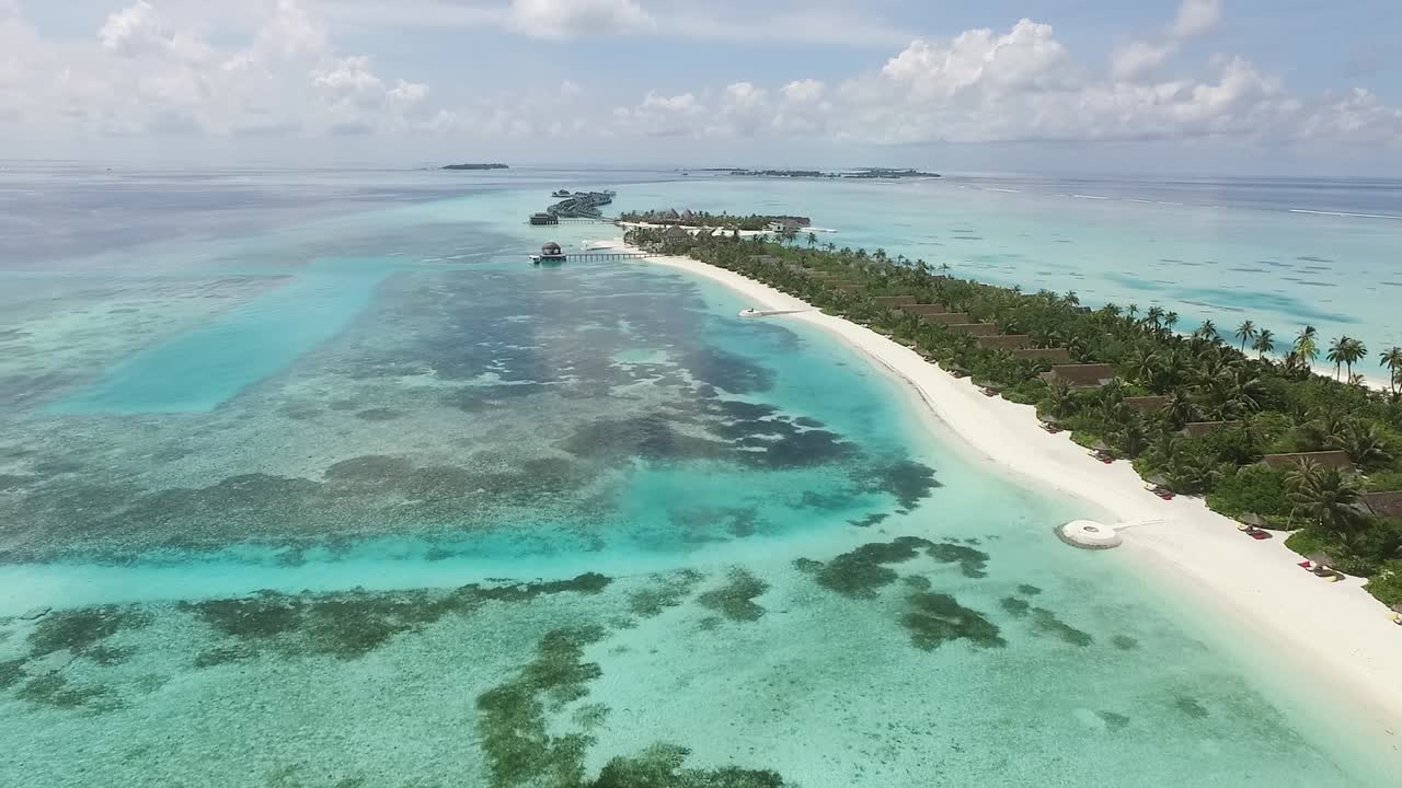 Suggestiva ripresa con drone di un resort alle Maldive dall'alto, acqua blu e turchese