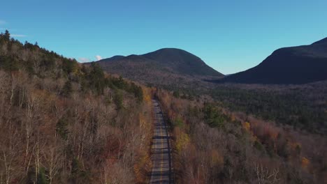 Mountainside-road-in-a-dry-tree-forest-with-a-blue-sky-in-New-Hampshire,-USA