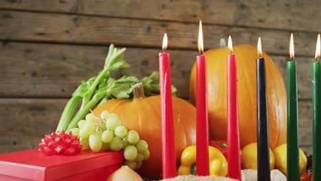 composition of seven lit candles and halloween pumpkins, present and vegatables