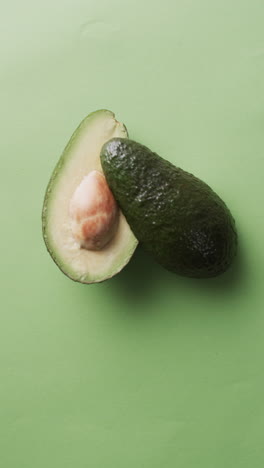 vertical video of sliced avocado with copy space over green background