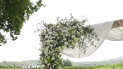 Wood-frame-decorated-with-white-flowers-and-fabric-flying-with-the-wind-in-Quinta-da-Pacheca,-Lamego,-Portugal