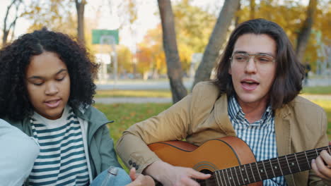 friends playing guitar in autumn park