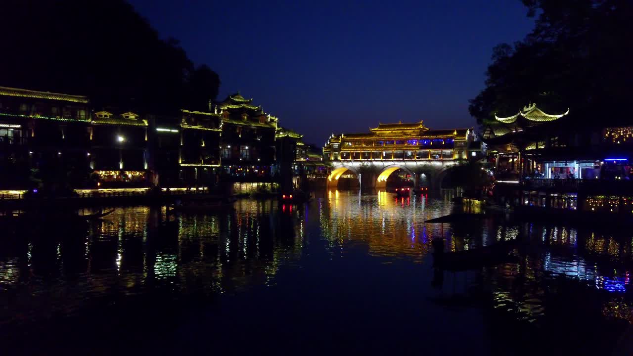 Antiga ponte em arco histórica iluminada à noite nas margens do rio Tuo, fluindo pelo centro da Cidade Antiga de Fenghuang, China