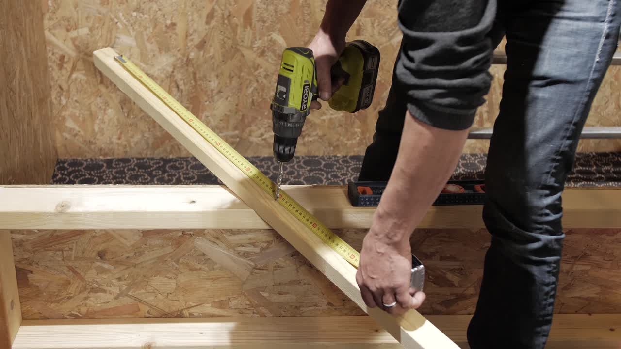 Worker measuring and drilling wood plank for precise construction setup