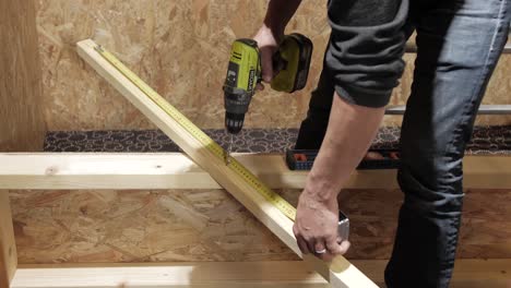 worker measuring and drilling wood plank for precise construction setup