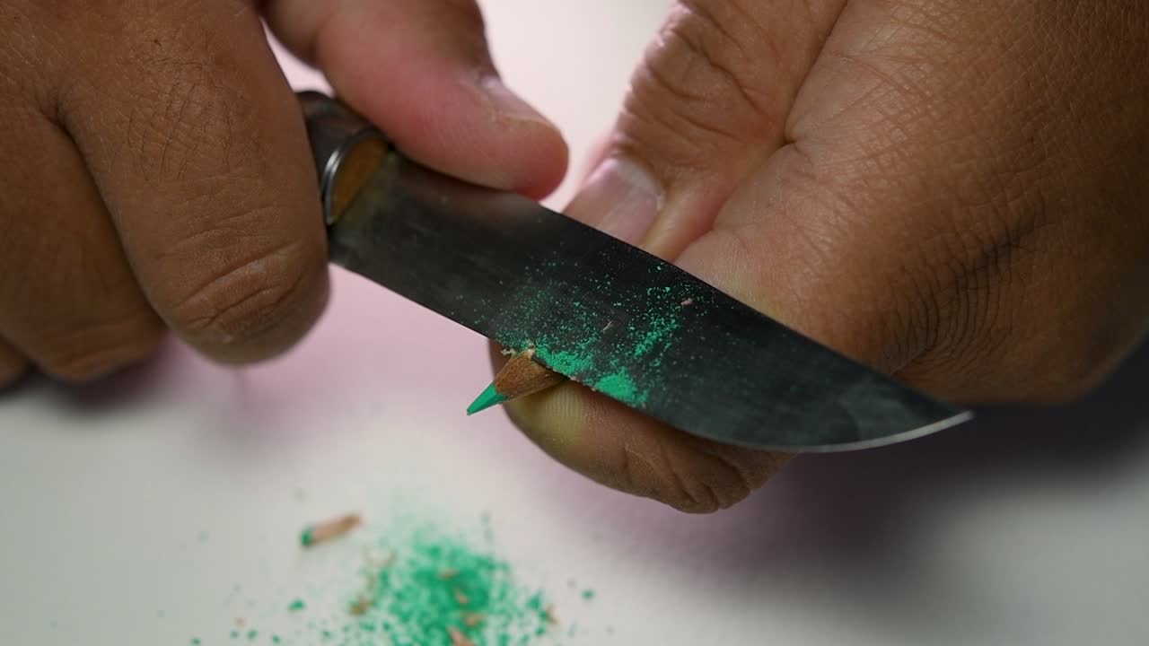 날카로운 칼로 연필과 색연필을 천천히 갈고 있는 손의 영상