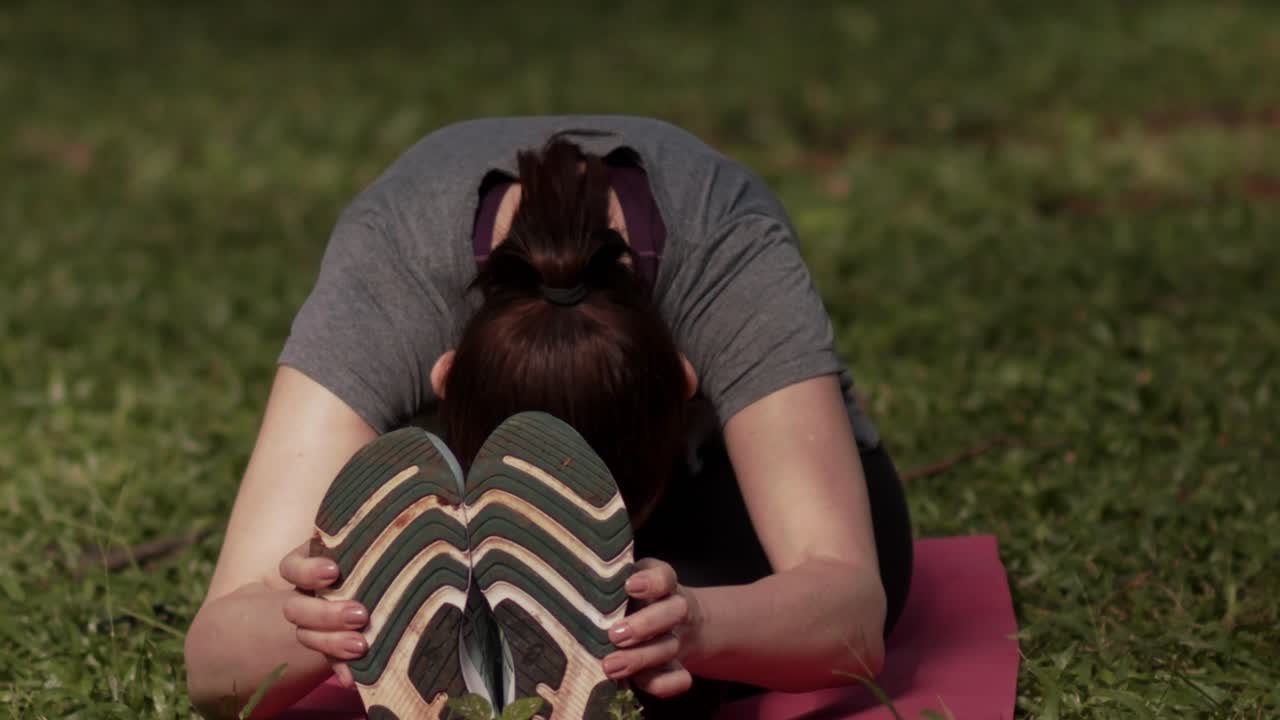 una mujer sentada se estira en la naturaleza, en cámara lenta.