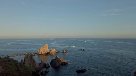 Distant-View-Of-Boats-Cruising-Across-The-Sea-At-Sunset,-Seen-From-Playa-La-Calilla-In-Spain