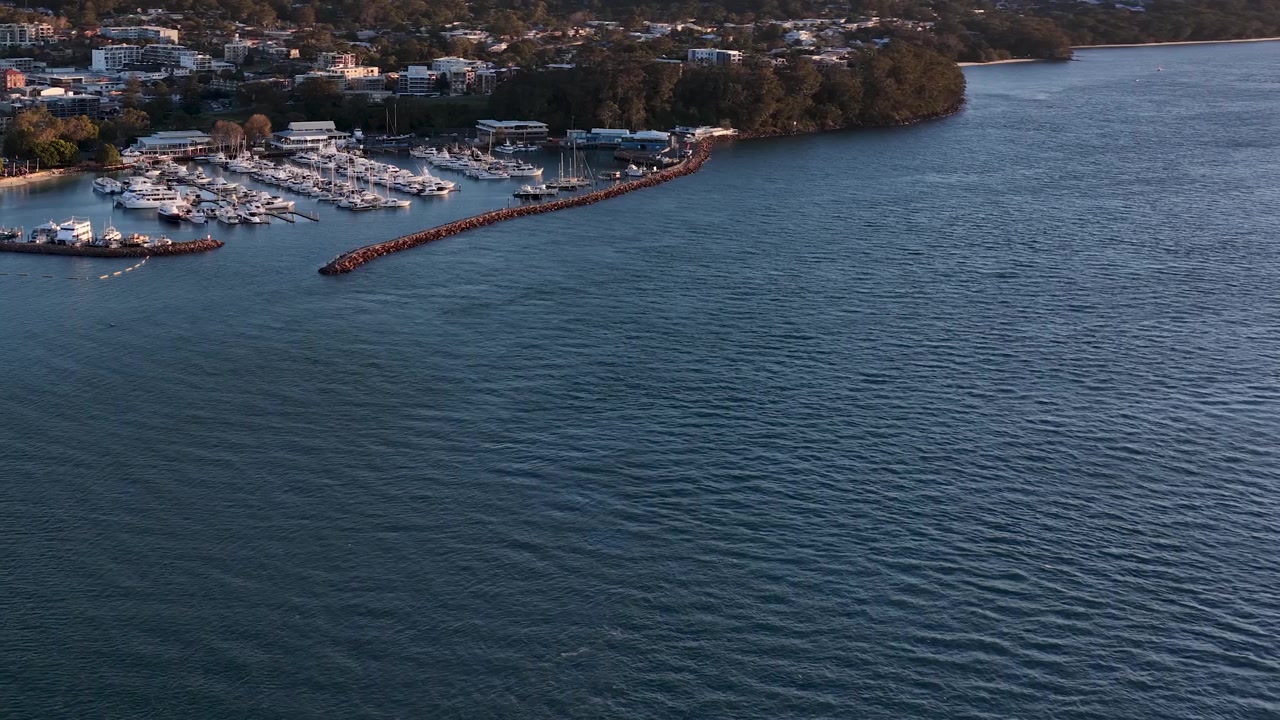 High-angle aerial shot of boats moored in Nelson Bay marina during golden hour, Australia.
