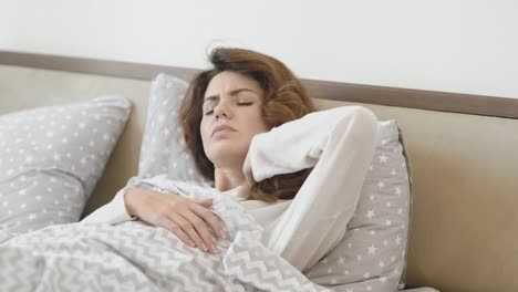 Beautiful-woman-waking-up-in-bed-in-morning.-Sick-woman-massaging-neck.