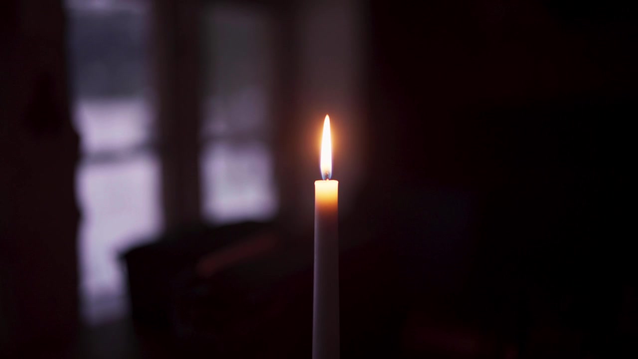 Bougie allumée brillant dans une pièce sombre. Gros plan.