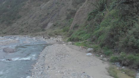 three men standing on the edge of mountain dirt road vehicle tracks leading out to riverbed opening boulders rocks sand i valley kabayan benguet philippines fast reverse revealing people aerial
