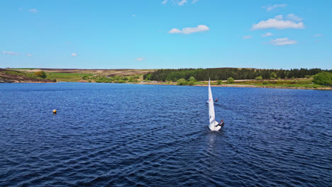 the peaceful winscar reservoir in yorkshire transforms into a hub of excitement as small one-man boats take part in a lively sailing event, showcasing the sport's leisurely side