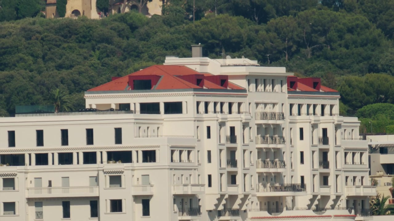 Edifício de hotel de luxo branco com telhados vermelhos com vista para a cidade de Cannes, incorporando elegância e viagens para a Riviera Francesa
