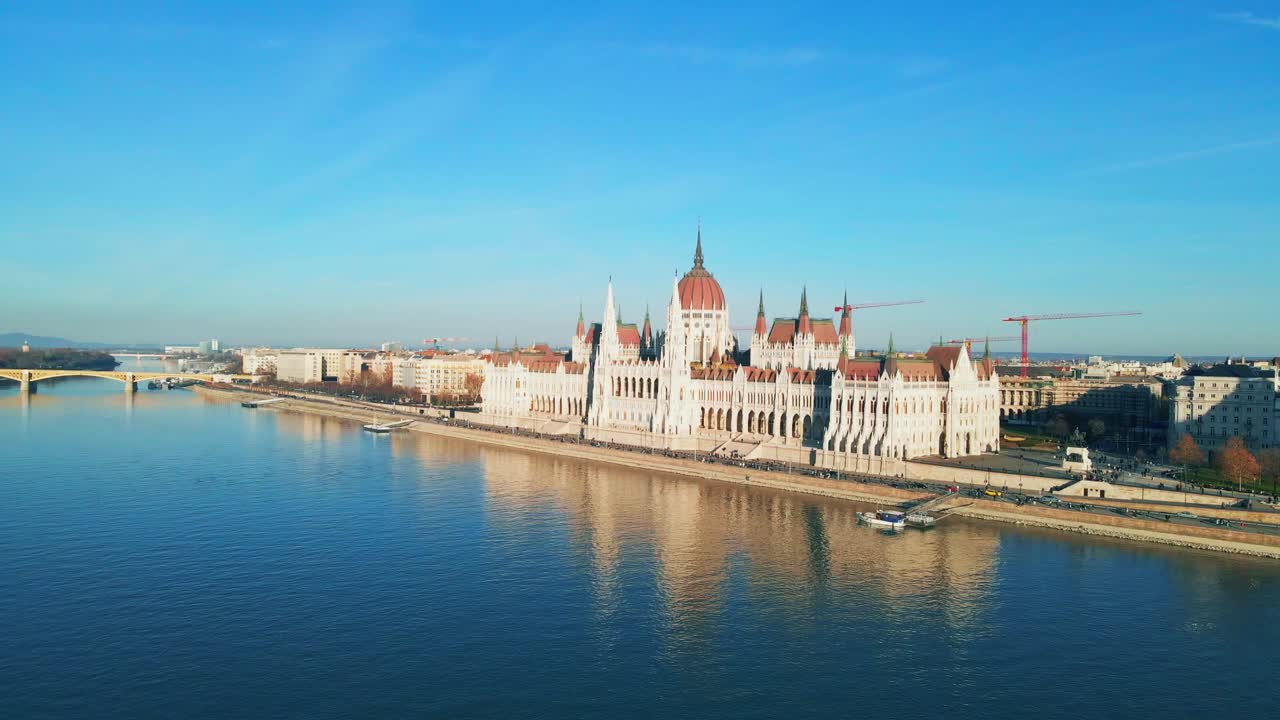 Un drone si avvicina lentamente al Parlamento di Budapest sopra il fiume Danubio, con lo skyline della città e i riflessi