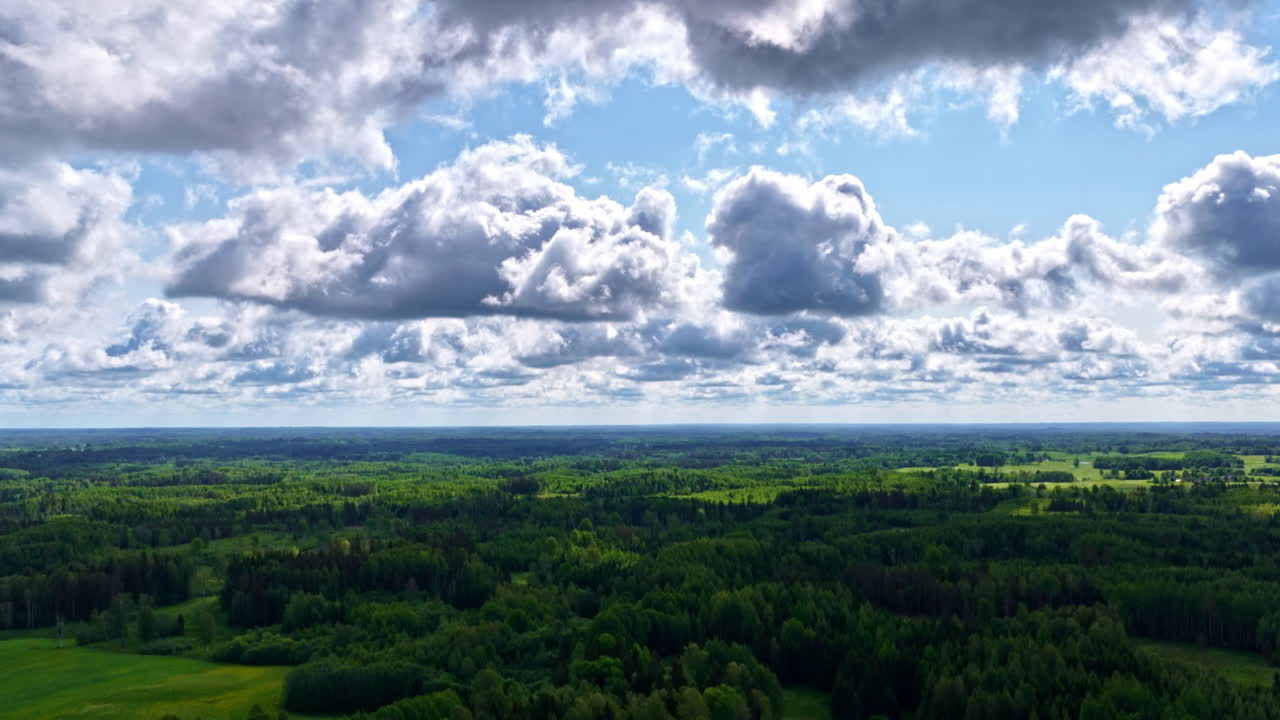 Vast green landscape with dramatic sky and scattered cloud formations