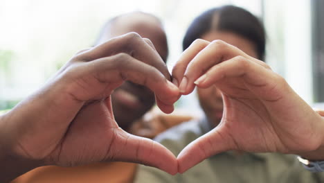 una pareja diversa forma una forma de corazón con sus manos