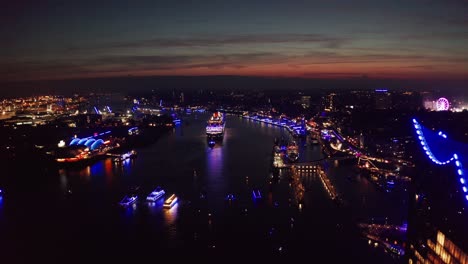 Queen-Mary-2-in-Hamburg-Harbour-during-Hamburg-Cruise-Days-with-blue-light-show-across-the-city-in-the-night-with-the-Elbphilharmonie-in-the-foreground