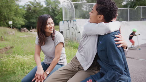 Three-Female-Friends-Talking-And-Laughing-In-Urban-Skate-Park